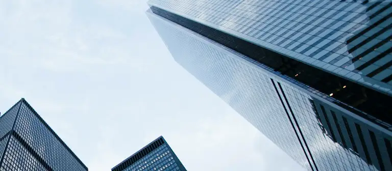 Glass office towers seen from below against an overcast sky